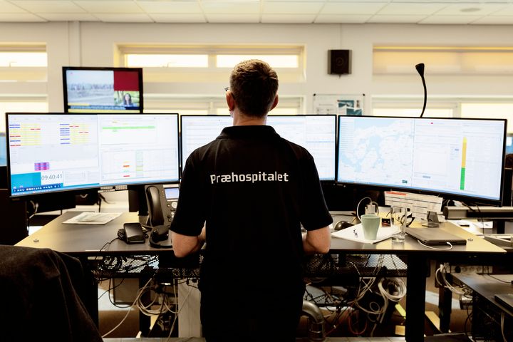 En person står foran flere computerskærme i en vagtcentral.