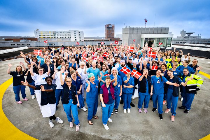 Her ses nogle af de mange medarbejdere, der har andel i, at AUH i år vinder førstepladsplaceringer inden for 11 behandlingsområder i konkurrence om Danmarks Bedste Hospital 2024. Billedet er taget på AUH's hjerte-helikopterplatform.