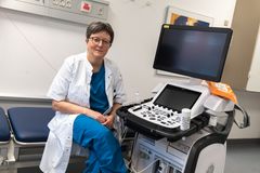 Kvindelig læge sidder ved måleapparat på hospitalsseng.