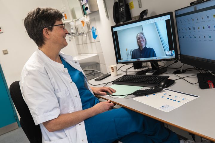 Kvindelig læge sidder i videokonsultation med en læge fra almen praksis.
