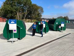 To personer står foran affaldscontainer.