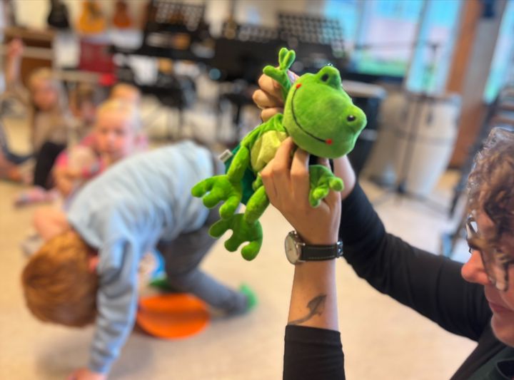 Den lille grønne figur MusikFrø, som nu er hoppet med børnene i skole.