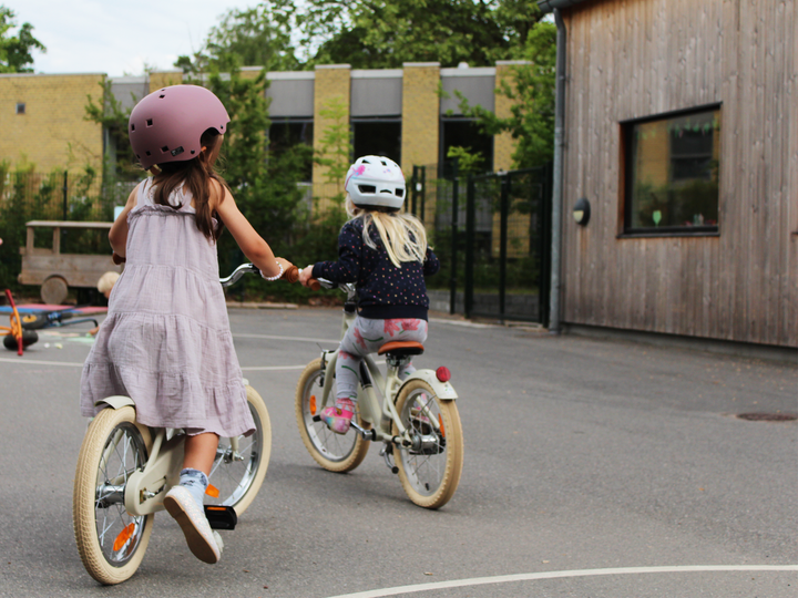 To børnehavepiger er med i cykelleg i Børnehuset Skovlyhuset