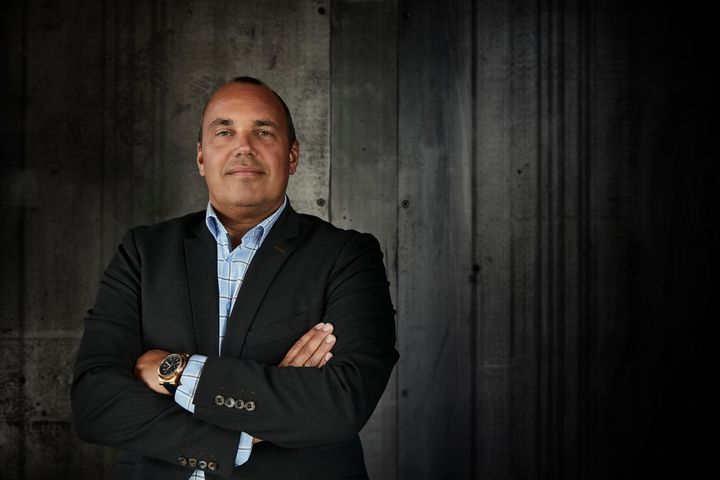 Thomas Vilstrup Jacobsen, kædechef i ejendoms mæglerkæden Estate i jakkesæt står med korslagte arme foran en mørk baggrund.