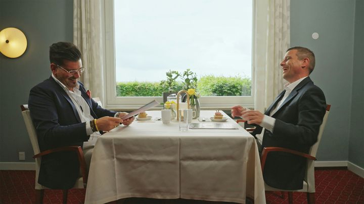 Bahadir Demirhan, Nybolig Odense og Peder Kongsgaard sidder ved et bord på en restaurant og griner sammen.