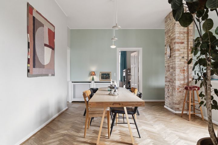 Spisestue%20med%20et%20langt%20tr%E6bord%2C%20moderne%20kunst%20p%E5%20v%E6ggen%20og%20parketgulv.