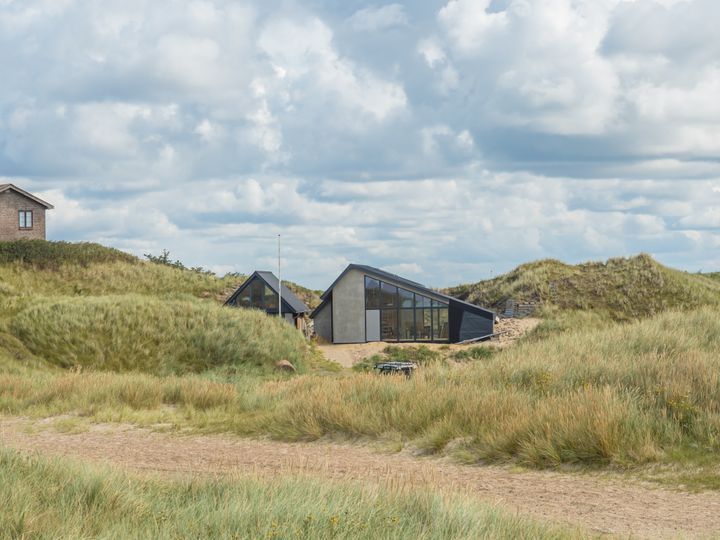Et%20moderne%20hus%20omgivet%20af%20klitter%20ved%20stranden.