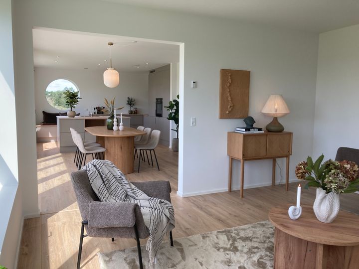 Stilfuldt indrettet stue og spiseområde i lyse nuancer med moderne møbler.