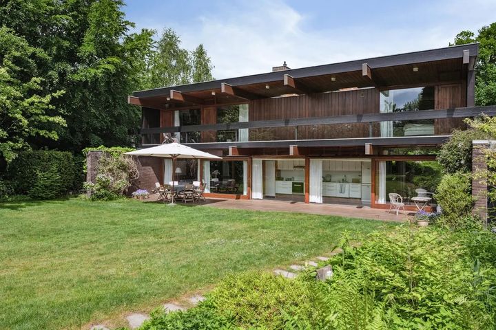 Moderne%20to-etagers%20hus%20med%20store%20glaspartier%2C%20tr%E6detaljer%20og%20en%20rummelig%20terrasse%20ud%20mod%20en%20gr%F8n%20have.