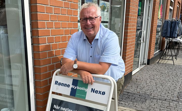 Søren Mortensen, indehaver af Nybolig Rønne & Nexø står smilende foran sin butik.