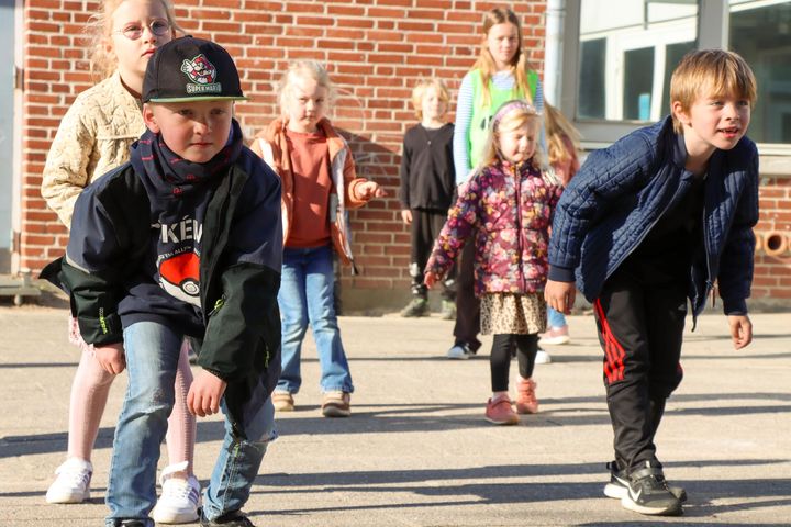 Børn leger i en skolegård. De ser meget koncentrerede ud.