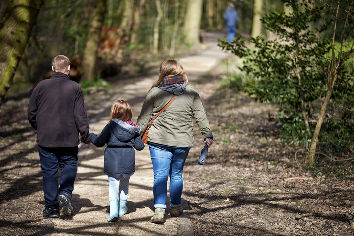 Familie på tur i skoven - far, mor og barn i midten. Sol og god stemning
