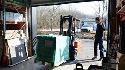 To personer arbejder sammen i en lagerbygning med en gaffeltruck.