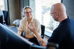 To mennesker taler sammen ved computerskærm