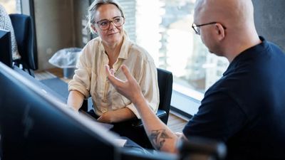 To mennesker taler sammen ved computerskærm