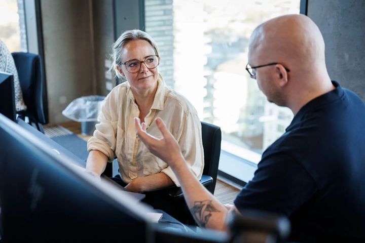 To mennesker taler sammen ved computerskærm