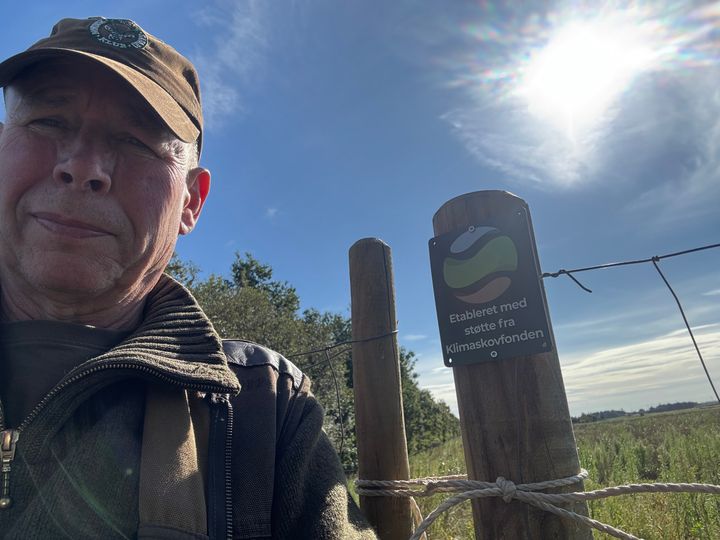 foto af landmand foran skilt på mark