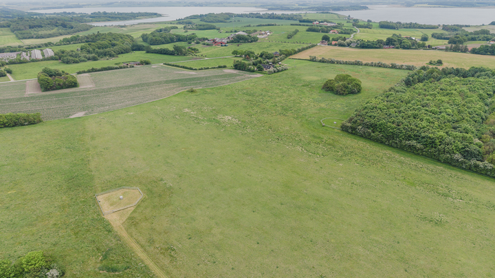 dronefoto af landskab med marker, skov og fjord