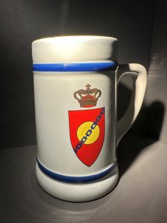 Krus med Forsvarets Central Radios logo, rød og gul skive og krone.