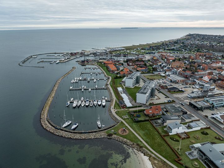 Billedet er et dronefoto af Juelsminde lystbådehavn, med udsigt over hele byen og kysten langs byen.