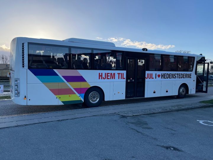 På billedet ser man en hvid bus med Hedensted Kommunes logo, og teksten: "Hjem til jul i Hedenstederne".