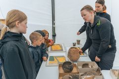 Et billeder af ansatte ved Vejle Museerne, som viser interesserede børn, hvad der er fundet langs vejen i løbet af anlægsfasen.