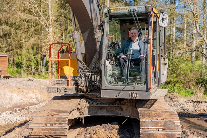 Formanden%20for%20Udvalget%20for%20Teknik%2C%20Viggo%20Kj%E6r%20Poulsen%2C%20sidder%20i%20en%20gravemaskine%2C%20efter%20han%20har%20brugt%20maskinen%20til%20at%20fjerne%20en%20blokering%20i%20%E5en.