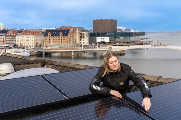 Kvinde tjekker solceller på tag i København
