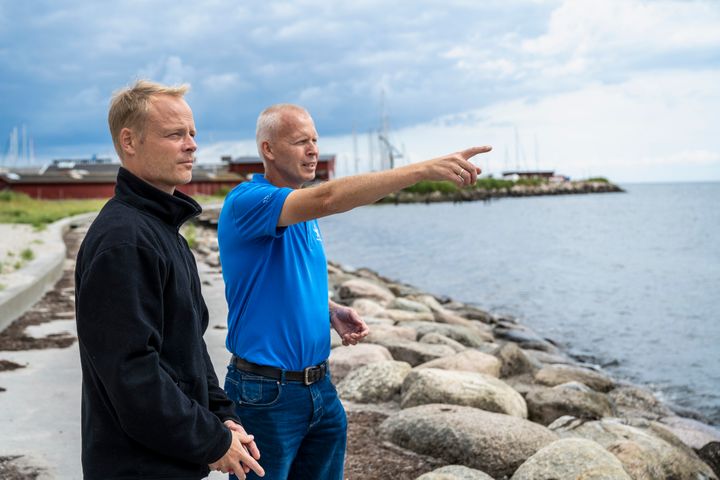 Thomas Behrendt Klinggaard (til venstre), chefkonsulent i HOFOR, sammen med Allan Scheller, formand for Køge Bugt Stenrev, der står bag de anlagte stenrev i Køge Bugt. De står på stranden og kigger ud over Køge Bugt.