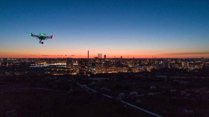 Drone flyver over Amagerfælled, billedet er taget om natten, og himlen lyser orange op.