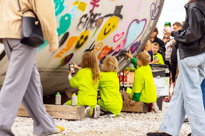 Børn skriver en hilsen til fremtiden på det store tunnelrør sammen med graffitikunstnere fra Institut for Urban Kunst.