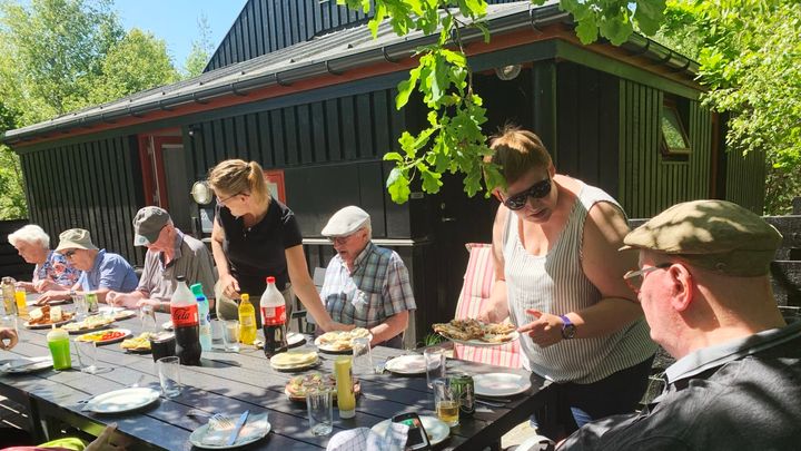 Frokosten indtages i det grønne. Beboere og medarbejdere fra Hiort Lorenzen spiser frokosten sammen ved sommerhuset i Dronningens Ferieby.