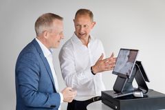 Karsten Henriksen, adm. direktør i Shopbox, illustrerer kasseløsningen for Nokas adm. direktør Morten Kierkegaard. Den samlede digitale løsning til modtagelse af betaling, herunder kontanter, betyder, at de erhvervsdrivende sparer tid på optælling af kontanter og afstemning, og at det bliver muligt at følge kontanterne, fra betalingen er registreret, til pengene er på virksomhedens konto.