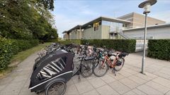 Foto af mange cykler i forgrunden og i baggrunden ses Møllehøjhallen.