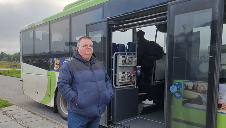 Transportordfører Niclas Aarestrup står og spejder fortan bus med udstigningsdøren åben.