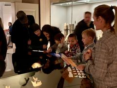 Familier samlet om en montre på Københavns Museum mens de ser på børneguiden