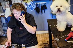 Kvinde der taler i telefon ved siden af en hvid hund