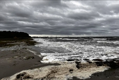 Foto af kysten, hvor man kan se at vandet er oprørt og at himlen er dramatisk.