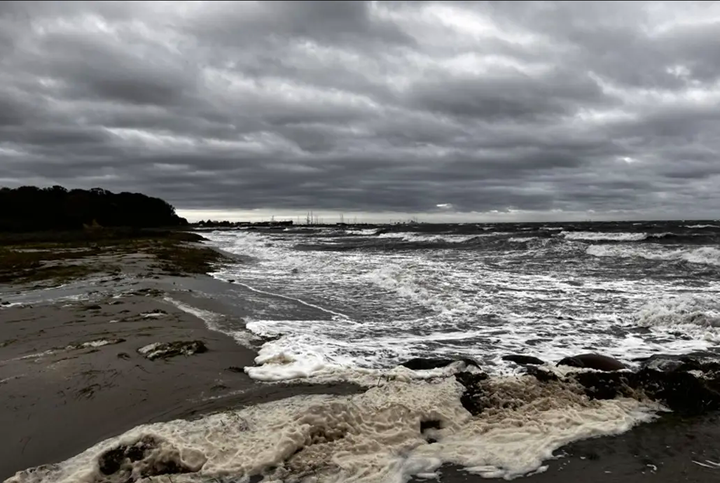 Foto af kysten, hvor man kan se at vandet er oprørt og at himlen er dramatisk.