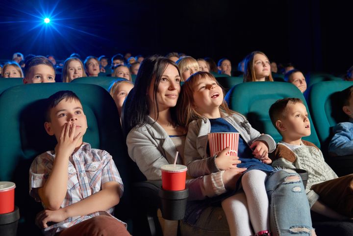 En gruppe børn og en voksen ser en film i en biograf.