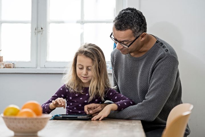 Barn og voksen kigger på en tablet.