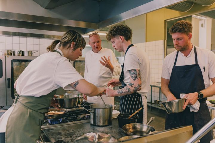 Fire kokke arbejder sammen i et køkken.
