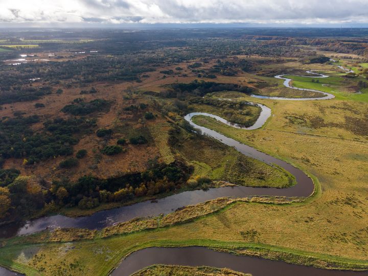 Luftfoto af en snoet flod, der løber gennem en grøn og brun vildmark.