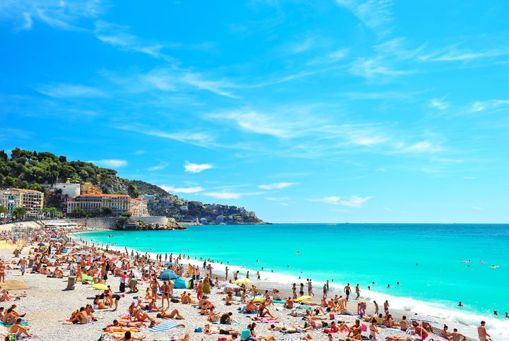 Hvid sandstrand fyldt med mennesker ved et turkisblåt hav