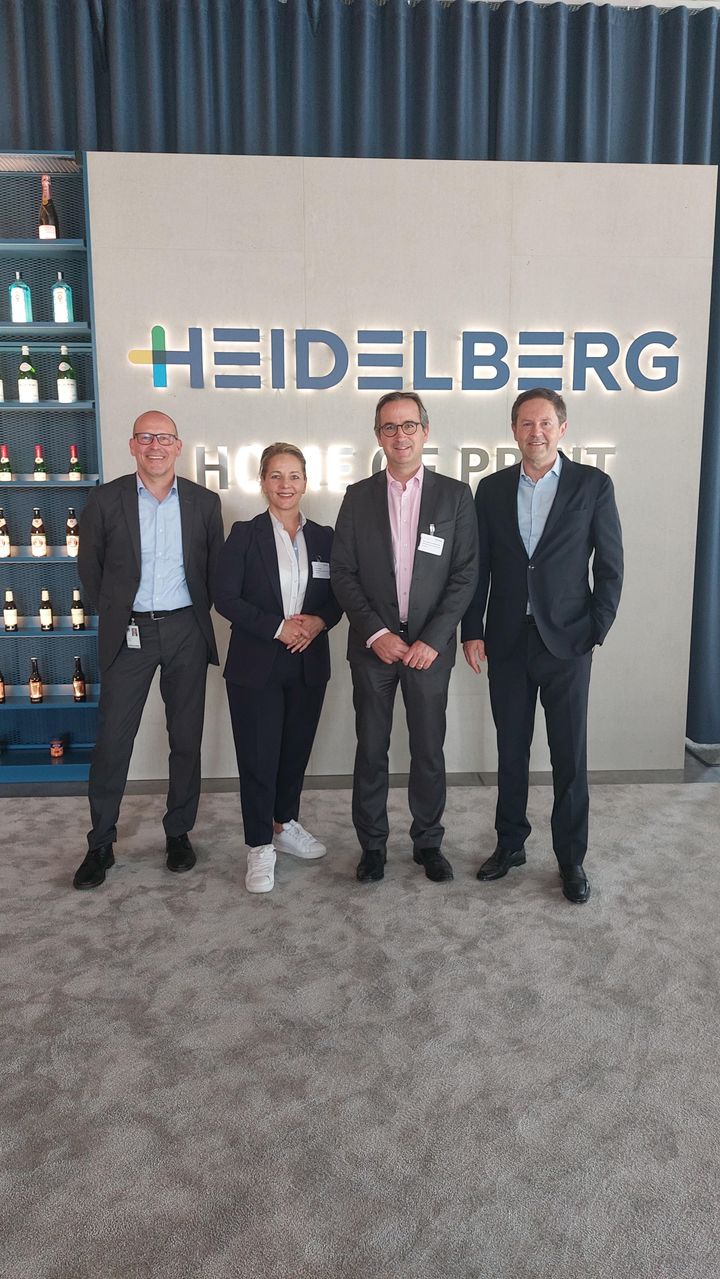 Image of four people standing in front of a sign that reads "HEIDELBERG" during a strategic partnership announcement with VINCORION.