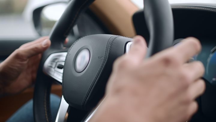 Hænder holder på rat i bil