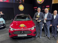 Mercedes-Benz repræsentant får overrakt The Car of the Year-trofæ foran rød bil