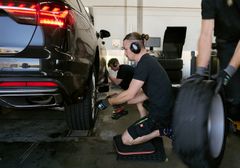 Testassistenter skifter hjul på sort bil