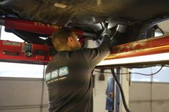 Testassistent undersøger undervogn på bil på lift