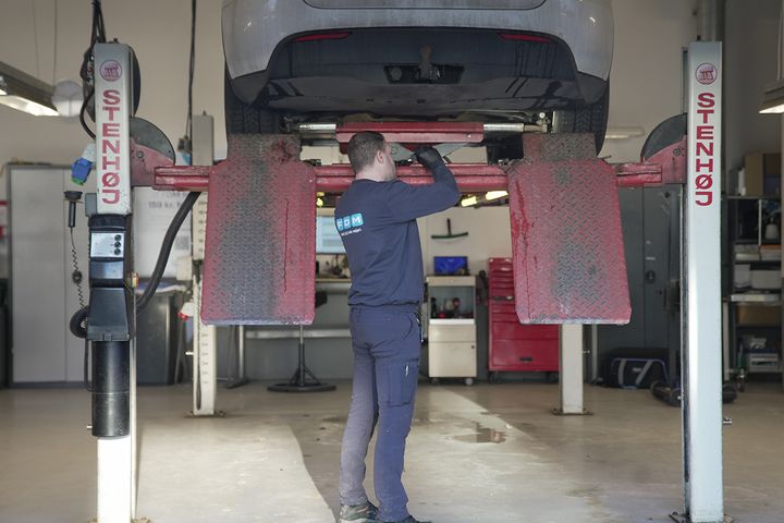 Testassistent gennemgår bil på lift